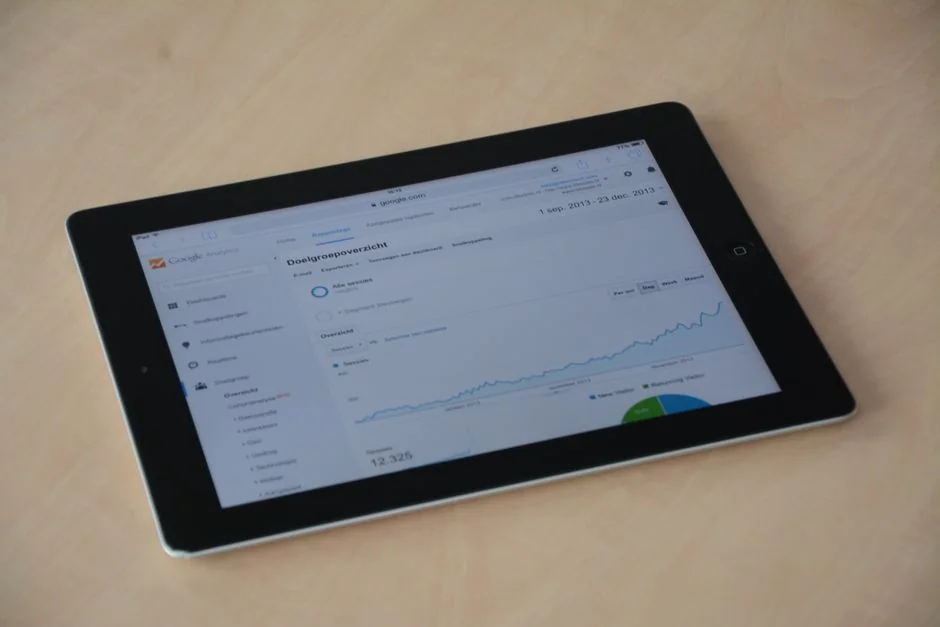 Two businessmen analyze stock market data using a smartphone and laptop in a modern office setting.